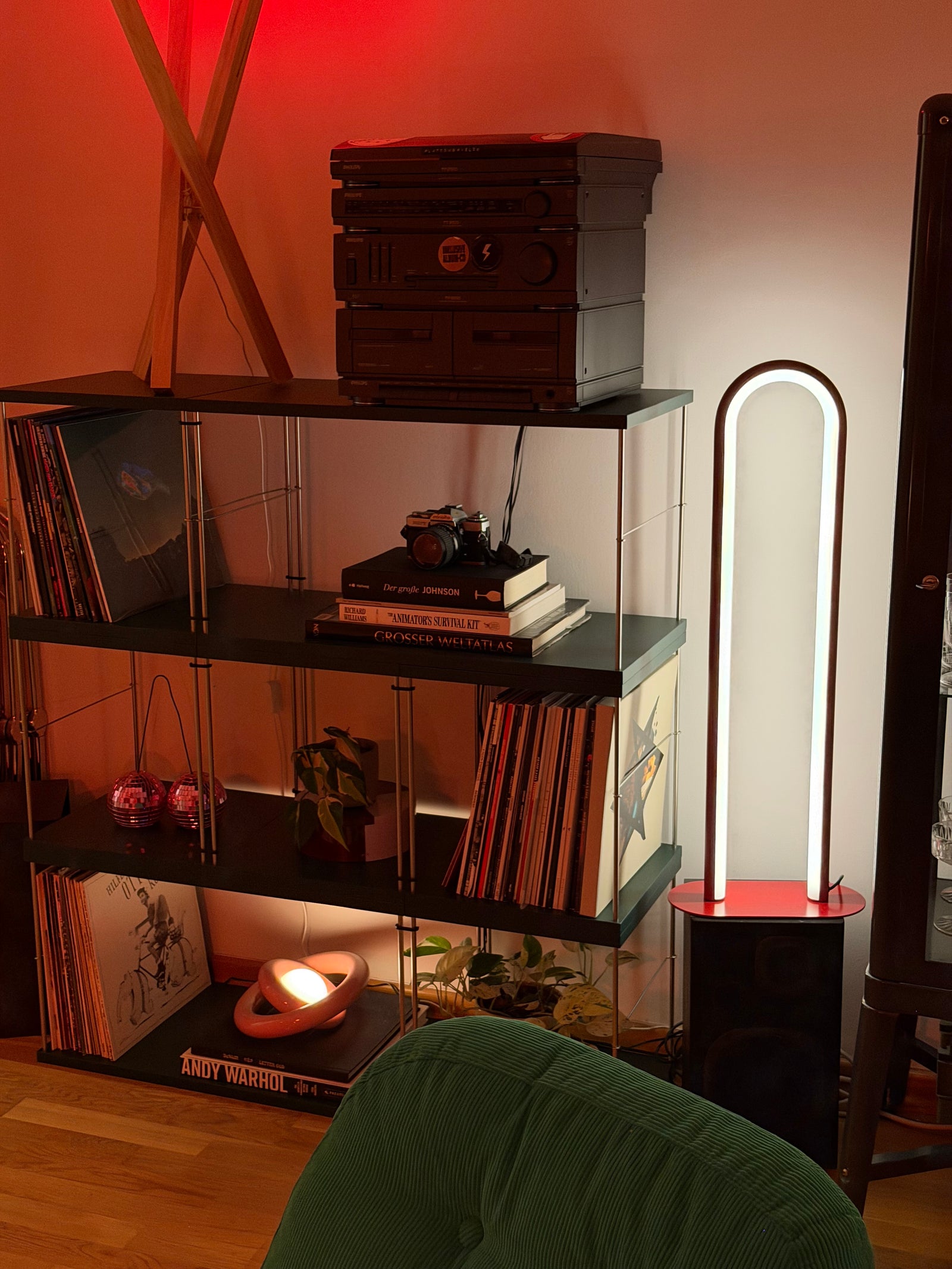 In einem grünen Bloks Regal stehen Schallplatten, ein HIFI System und Bücher